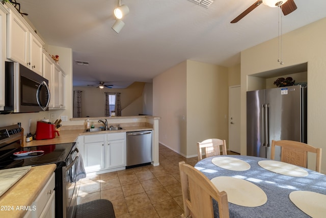 kitchen with white cabinetry, sink, kitchen peninsula, light tile patterned flooring, and appliances with stainless steel finishes