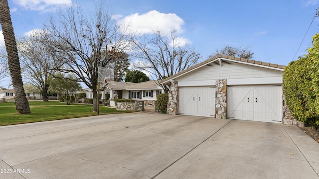 ranch-style home with a garage, stone siding, concrete driveway, and a front yard