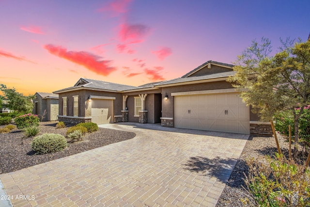 view of front of house featuring decorative driveway, stucco siding, a garage, stone siding, and a tiled roof