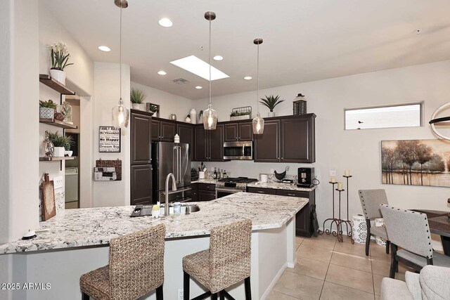 6937 E Purple Shade Cir, Scottsdale, AZ 85266 - kitchen with appliances with stainless steel finishes, a peninsula, a skylight, light tile patterned floors, and a sink