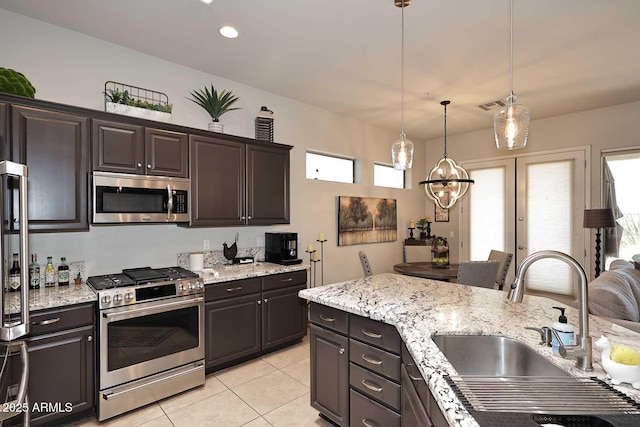 6937 E Purple Shade Cir, Scottsdale, AZ 85266 - kitchen featuring stainless steel appliances, a sink, light tile patterned flooring, decorative light fixtures, and light stone counters