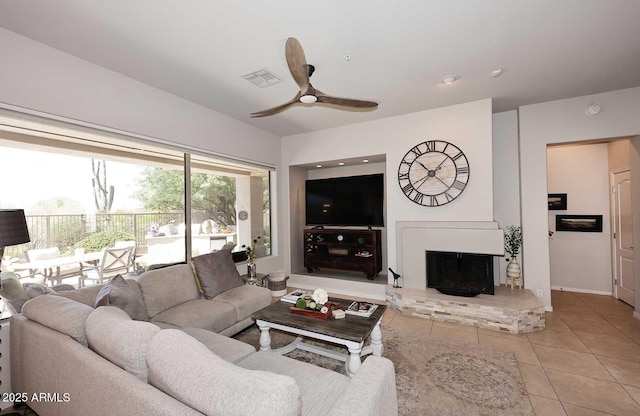 6937 E Purple Shade Cir, Scottsdale, AZ 85266 - living room with light tile patterned floors, ceiling fan, a fireplace with raised hearth, and baseboards