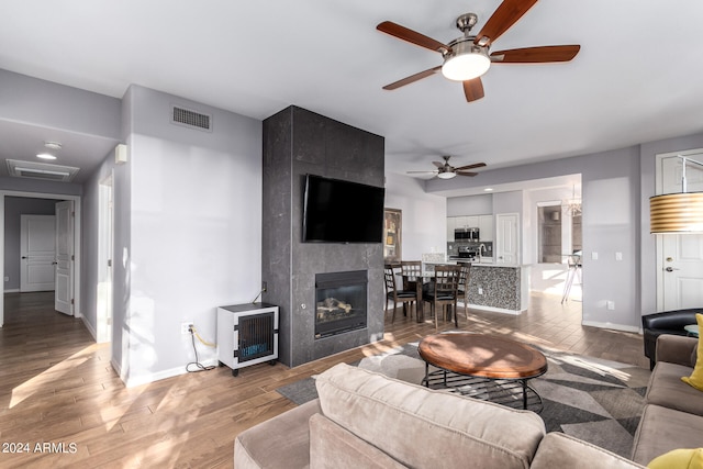 living room featuring a fireplace, wood-type flooring, and ceiling fan