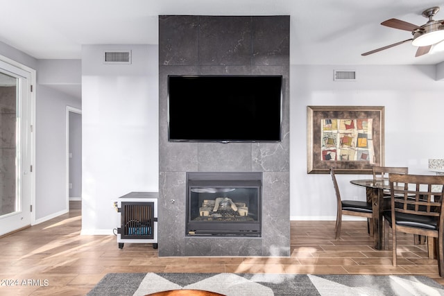 living room featuring hardwood / wood-style floors, ceiling fan, and a fireplace