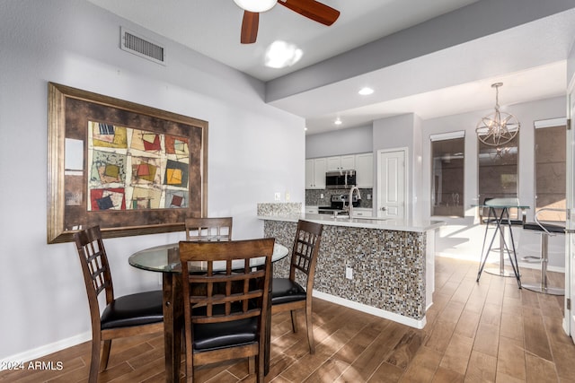 dining room with ceiling fan with notable chandelier and dark hardwood / wood-style floors