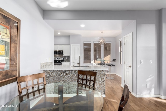 dining room featuring light wood-type flooring, a chandelier, and sink