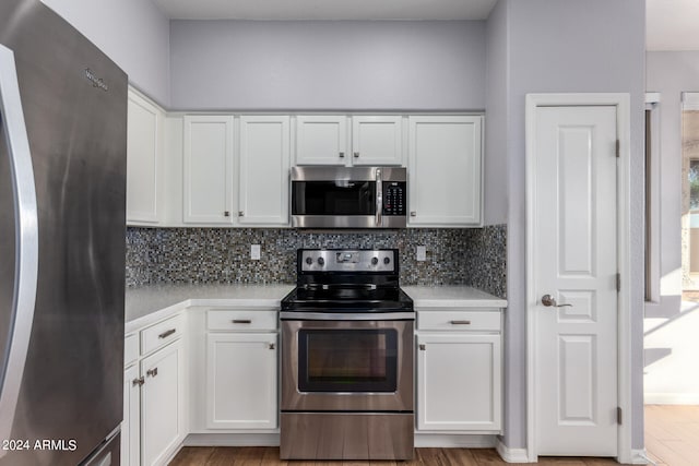 kitchen with light wood-type flooring, appliances with stainless steel finishes, and white cabinets