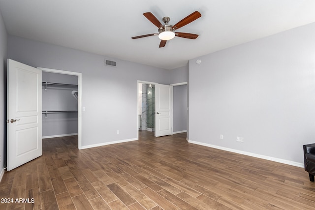 unfurnished bedroom with hardwood / wood-style floors, ceiling fan, a walk in closet, and a closet