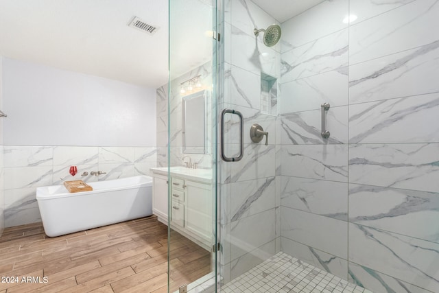 bathroom featuring vanity, tile walls, independent shower and bath, and hardwood / wood-style floors