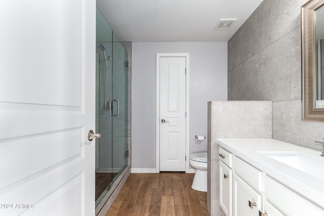 bathroom featuring walk in shower, vanity, toilet, and hardwood / wood-style floors