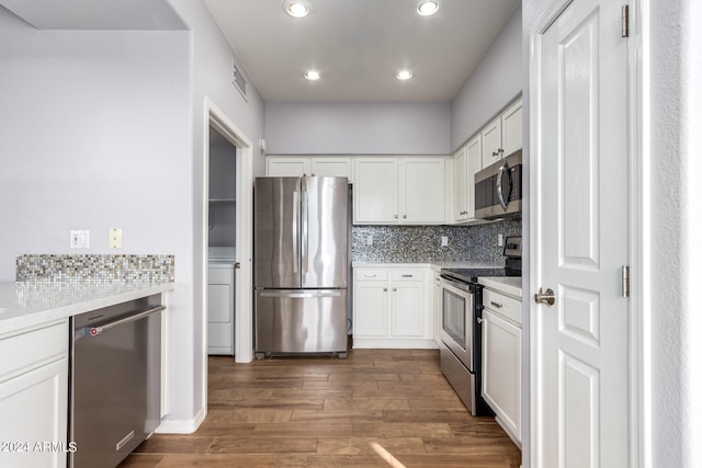 kitchen featuring white cabinetry, dark hardwood / wood-style flooring, decorative backsplash, appliances with stainless steel finishes, and washer / clothes dryer