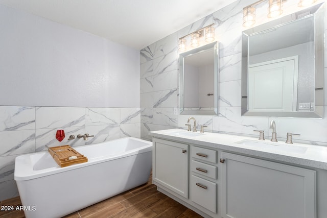 bathroom with hardwood / wood-style flooring, a bathing tub, tile walls, decorative backsplash, and vanity