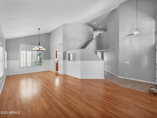 981 N Quail Ln, Gilbert, AZ 85233 - unfurnished living room featuring a chandelier, wood finished floors, high vaulted ceiling, and wainscoting