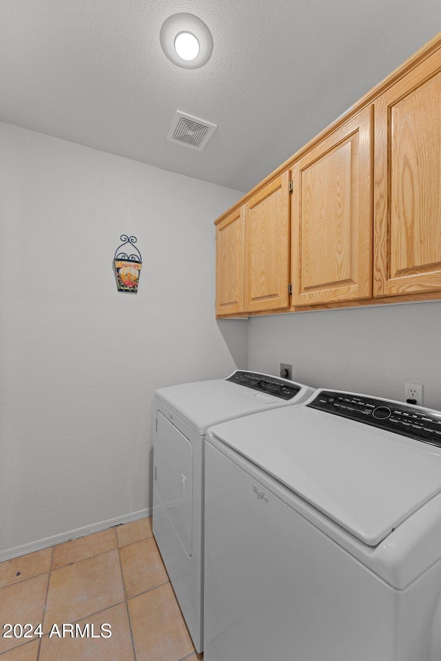 clothes washing area featuring cabinets, light tile patterned floors, and separate washer and dryer