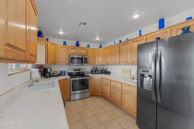 kitchen with sink, light tile patterned flooring, light brown cabinets, and appliances with stainless steel finishes