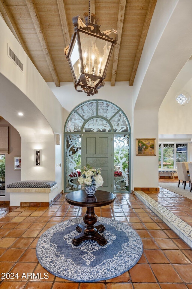 tiled entrance foyer featuring beam ceiling, wood ceiling, and high vaulted ceiling