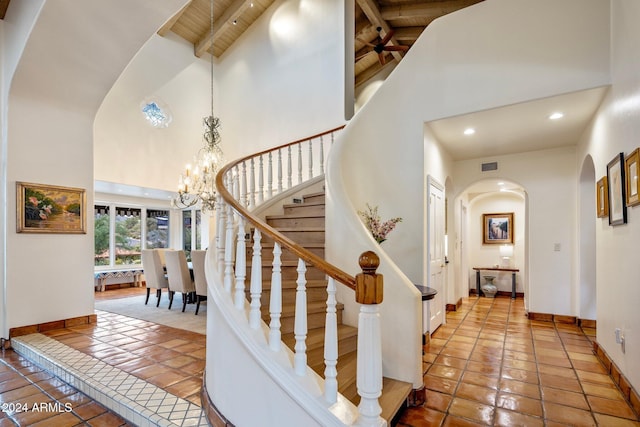 staircase with wooden ceiling, an inviting chandelier, tile patterned flooring, beamed ceiling, and high vaulted ceiling