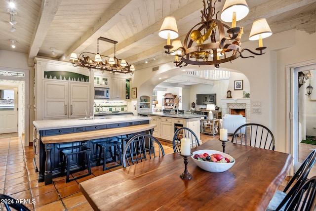 dining space with beam ceiling, wood ceiling, sink, and a chandelier