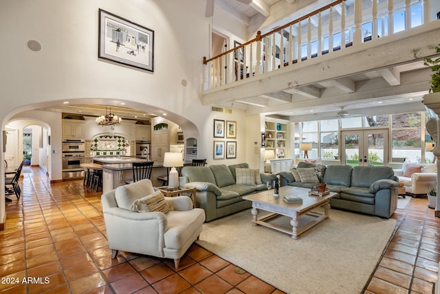 living room featuring tile patterned floors, beamed ceiling, and a high ceiling