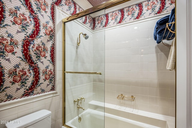 bathroom featuring shower / bath combination with glass door, tile walls, and toilet