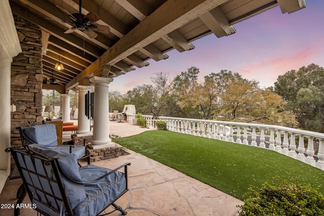 patio terrace at dusk featuring ceiling fan and a lawn