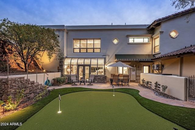 back house at dusk with ceiling fan and a patio area