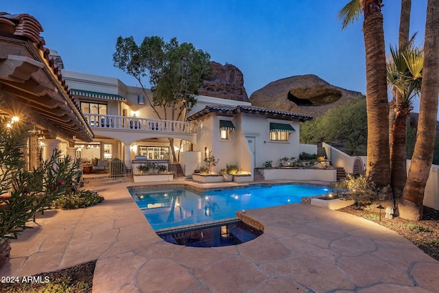 pool at dusk featuring an in ground hot tub, a mountain view, and a patio