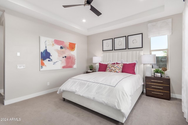 carpeted bedroom with ceiling fan and a tray ceiling