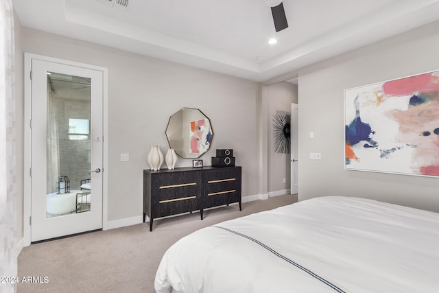 carpeted bedroom with ceiling fan and a raised ceiling