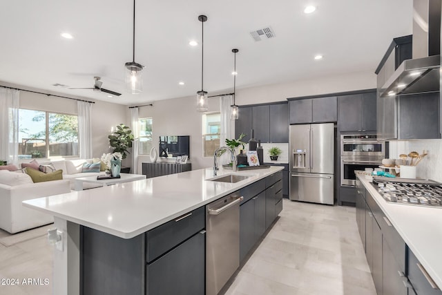 kitchen with stainless steel appliances, sink, ceiling fan, a spacious island, and pendant lighting