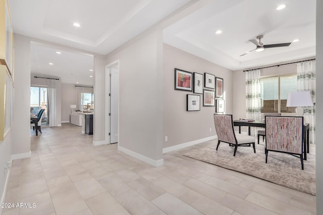 interior space featuring a wealth of natural light, ceiling fan, and a raised ceiling