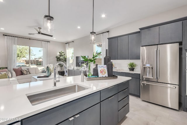 kitchen featuring high end refrigerator, ceiling fan, sink, and decorative light fixtures