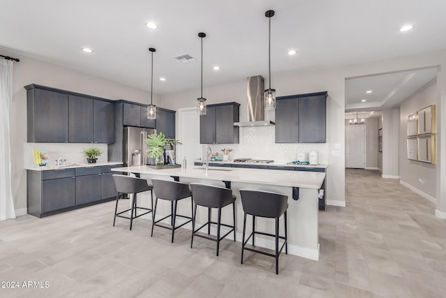 kitchen featuring hanging light fixtures, wall chimney exhaust hood, and a large island with sink