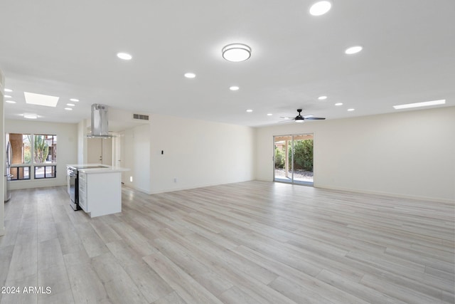 unfurnished living room with ceiling fan, a healthy amount of sunlight, and light wood-type flooring