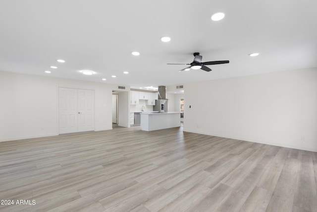 unfurnished living room with sink, light hardwood / wood-style floors, and ceiling fan