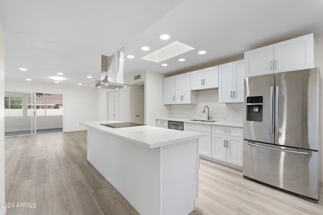 kitchen with appliances with stainless steel finishes, white cabinetry, light stone countertops, a skylight, and light hardwood / wood-style floors