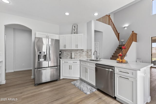 18132 W Cardinal Dr, Goodyear, AZ 85338 - kitchen featuring stainless steel appliances, a peninsula, white cabinets, light countertops, and tasteful backsplash
