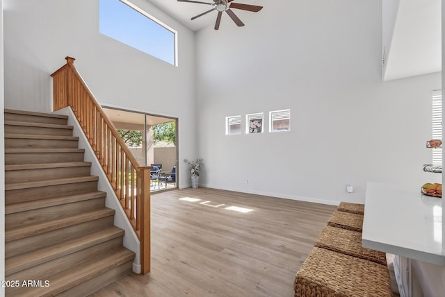 18132 W Cardinal Dr, Goodyear, AZ 85338 - unfurnished living room with a towering ceiling, ceiling fan, stairway, and wood finished floors