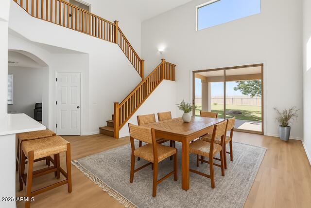 18132 W Cardinal Dr, Goodyear, AZ 85338 - dining area with a towering ceiling, arched walkways, light wood-style floors, and stairs