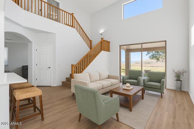 18132 W Cardinal Dr, Goodyear, AZ 85338 - living room featuring a towering ceiling, healthy amount of natural light, light wood-style flooring, arched walkways, and stairway
