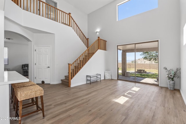 18132 W Cardinal Dr, Goodyear, AZ 85338 - unfurnished living room featuring a towering ceiling, wood finished floors, arched walkways, and stairway