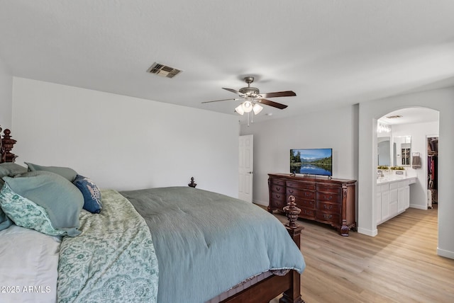 18132 W Cardinal Dr, Goodyear, AZ 85338 - bedroom featuring arched walkways, light wood-type flooring, ceiling fan, and connected bathroom