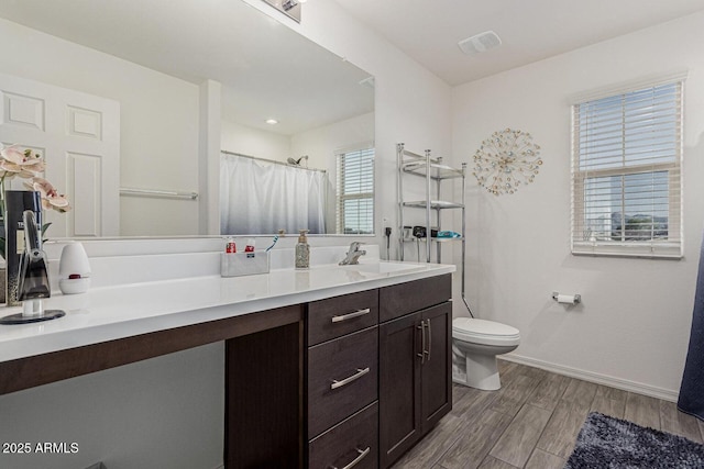 bathroom with vanity, baseboards, toilet, visible vents, and wood finished floors