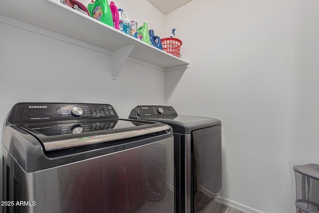clothes washing area with independent washer and dryer, laundry area, and baseboards