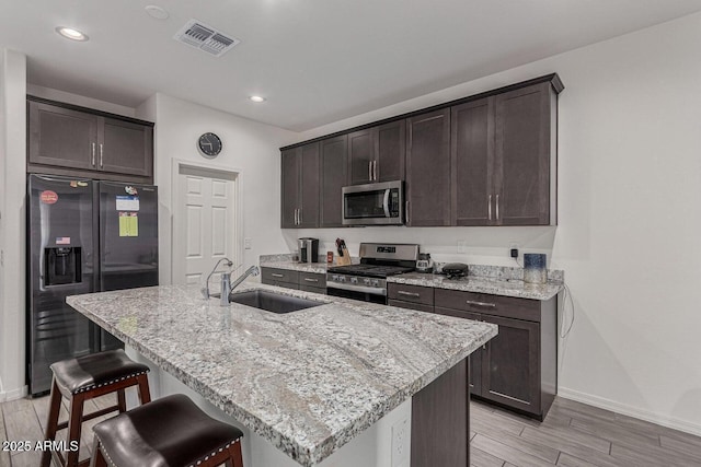 kitchen with light wood-type flooring, baseboards, visible vents, stainless steel appliances, and a sink