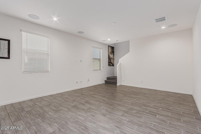 spare room with visible vents, recessed lighting, wood finished floors, stairs, and baseboards