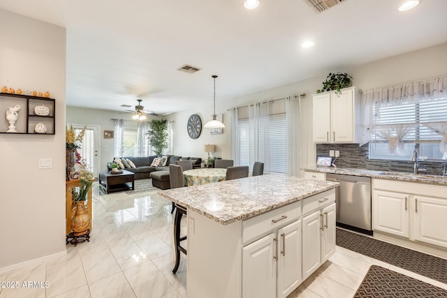 kitchen featuring a center island, white cabinetry, sink, hanging light fixtures, and stainless steel dishwasher