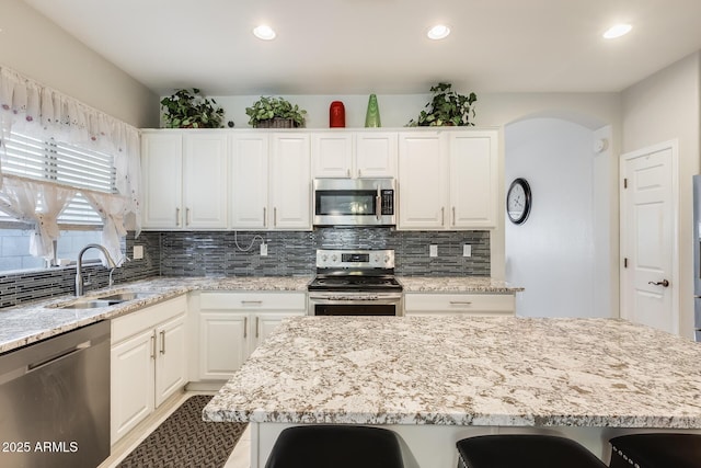 kitchen featuring sink, a kitchen island, white cabinetry, and appliances with stainless steel finishes