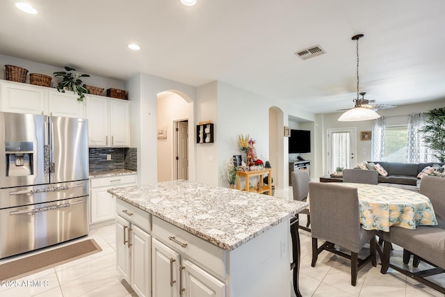 kitchen featuring decorative backsplash, white cabinetry, stainless steel fridge with ice dispenser, and a kitchen island