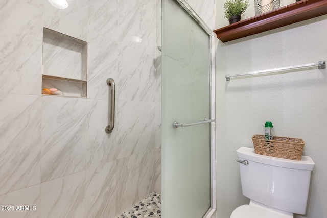 bathroom featuring a shower with door and toilet